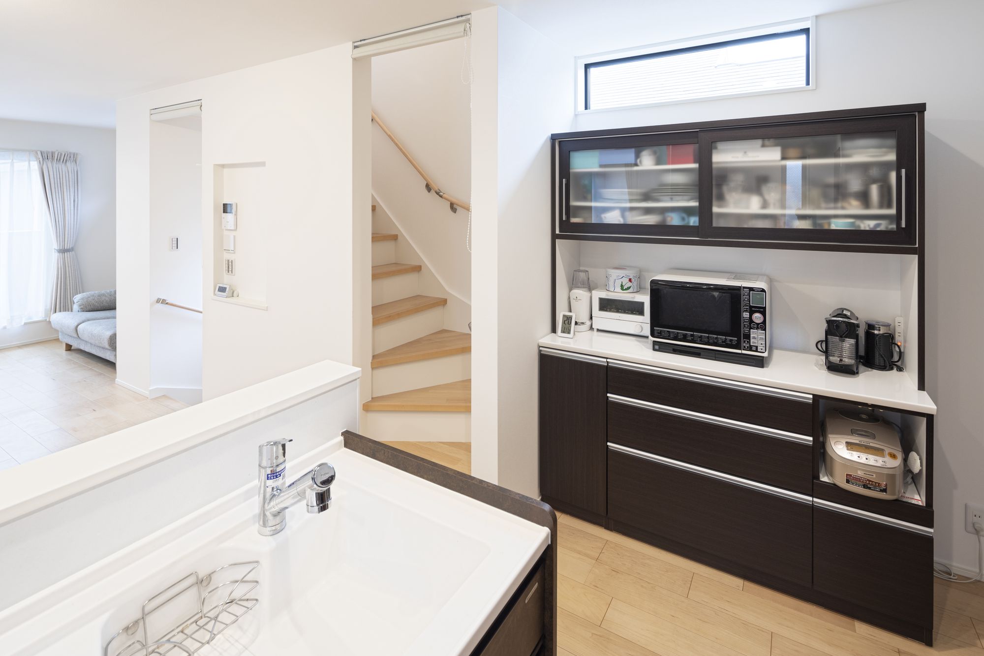 リビング階段の横の空間を活かしたキッチン収納。電子レンジ・トースター・コーヒーメーカーが使用できるようコンセントも設置。炊飯器もぴったり収納。